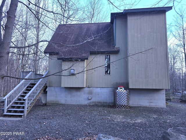 view of side of property featuring roof with shingles and stairs