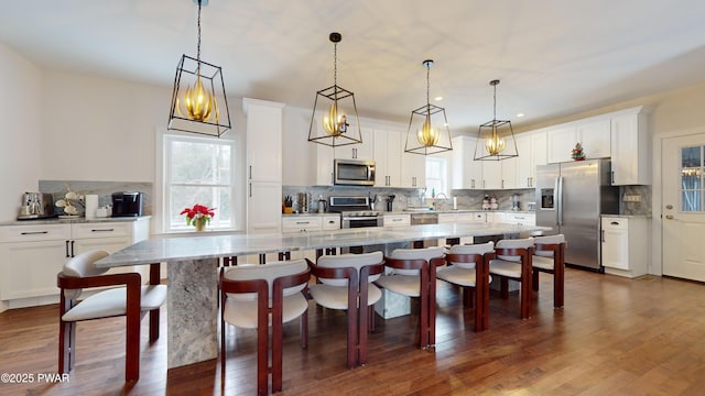 kitchen featuring hanging light fixtures, a spacious island, white cabinets, and appliances with stainless steel finishes