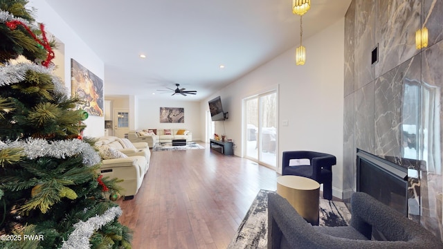 living room with hardwood / wood-style flooring, a large fireplace, and ceiling fan