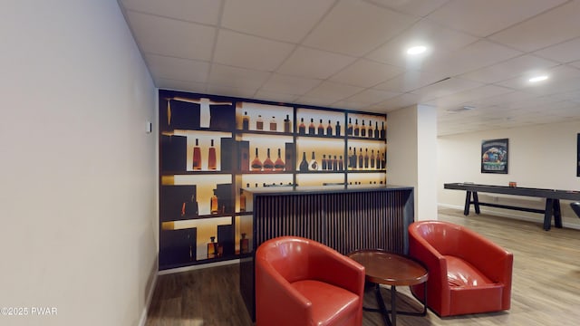 bar with a paneled ceiling and wood-type flooring