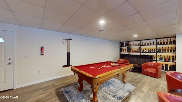 game room with hardwood / wood-style flooring, bar, and a drop ceiling