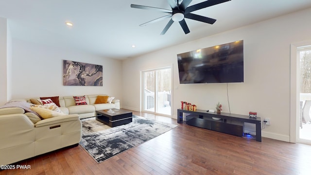 living room featuring dark wood-type flooring and ceiling fan