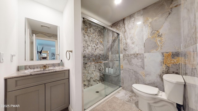 bathroom with a shower with door, vanity, tile walls, and toilet