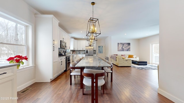 dining room featuring wood-type flooring, plenty of natural light, and a chandelier