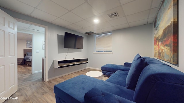 living room featuring a drop ceiling and light hardwood / wood-style flooring