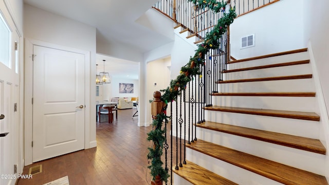 staircase featuring hardwood / wood-style flooring and a chandelier