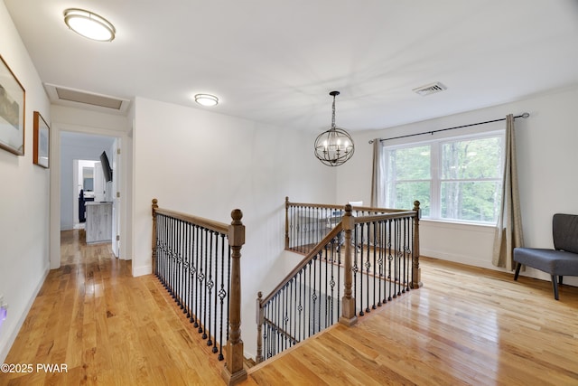 hall with light hardwood / wood-style flooring and a notable chandelier