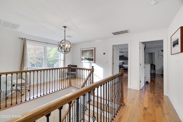 hallway featuring an inviting chandelier and light hardwood / wood-style flooring