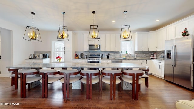 kitchen with white cabinetry, appliances with stainless steel finishes, a large island, and pendant lighting