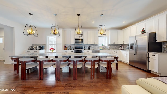 kitchen with hanging light fixtures, stainless steel appliances, white cabinets, and a kitchen island