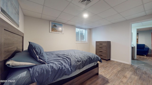 bedroom with wood-type flooring and a drop ceiling