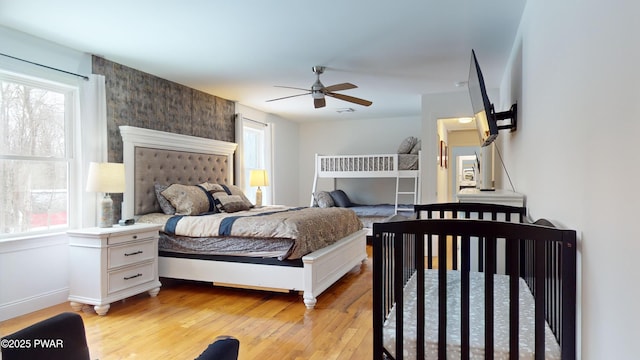 bedroom with ceiling fan, multiple windows, and light wood-type flooring