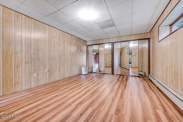 518 Lakeview Dr E, Lake Ariel, PA 18436 - empty room with a drop ceiling, a baseboard heating unit, wood finished floors, wood walls, and a baseboard radiator