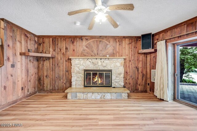 518 Lakeview Dr E, Lake Ariel, PA 18436 - unfurnished living room featuring wood finished floors, wood walls, a textured ceiling, a stone fireplace, and ceiling fan