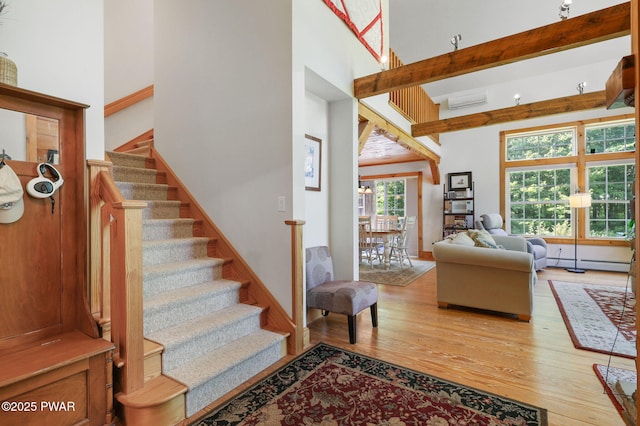 58 Rude Rd, Waymart, PA 18472 - stairway with wood finished floors, a baseboard radiator, an AC wall unit, a towering ceiling, and beam ceiling
