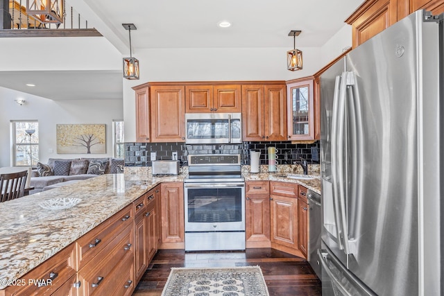 kitchen with backsplash, appliances with stainless steel finishes, brown cabinetry, and a sink