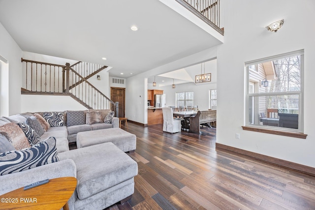 living area with visible vents, stairs, dark wood-style flooring, baseboards, and a chandelier