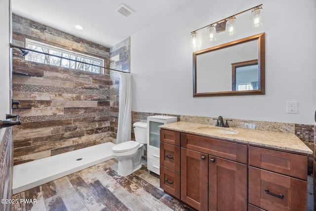 full bath with vanity, a tile shower, toilet, and wood finished floors