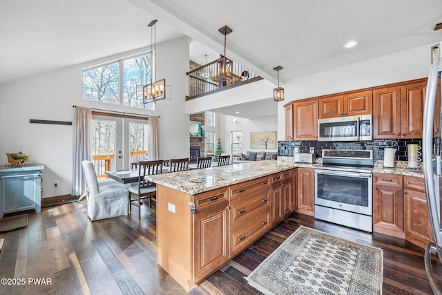 kitchen featuring dark wood finished floors, light stone countertops, stainless steel appliances, and a peninsula