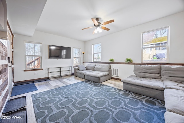 living room with ceiling fan, visible vents, a wealth of natural light, and wood finished floors