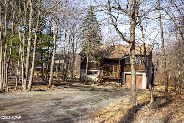 rustic home with a garage, driveway, and roof with shingles
