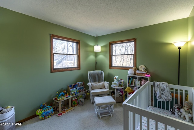 bedroom featuring a nursery area, carpet floors, and a textured ceiling