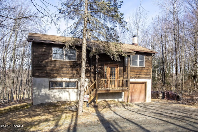 raised ranch with driveway, a chimney, and a garage