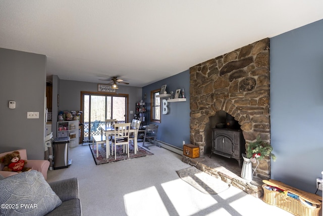 carpeted living area with a baseboard radiator, ceiling fan, and a wood stove