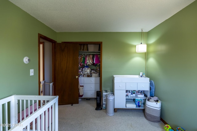 bedroom featuring a crib, a closet, carpet floors, and a textured ceiling