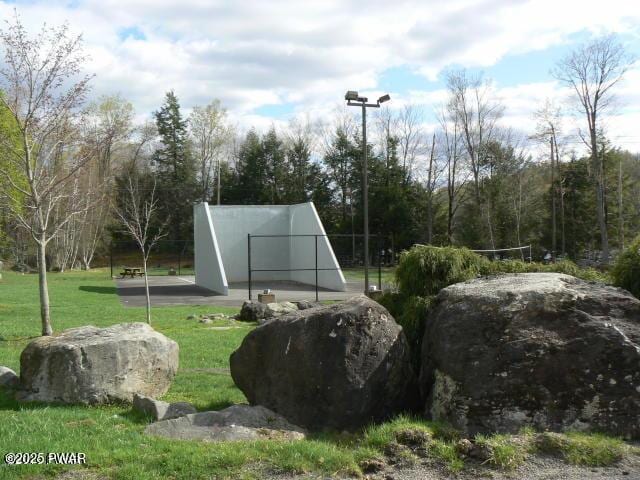 view of tennis court featuring a yard