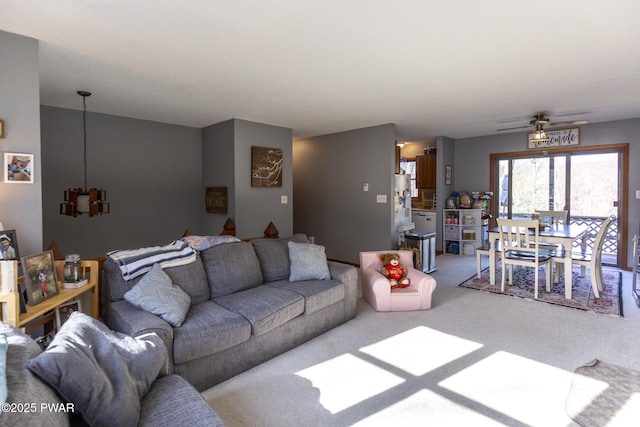 living area featuring ceiling fan with notable chandelier and carpet floors