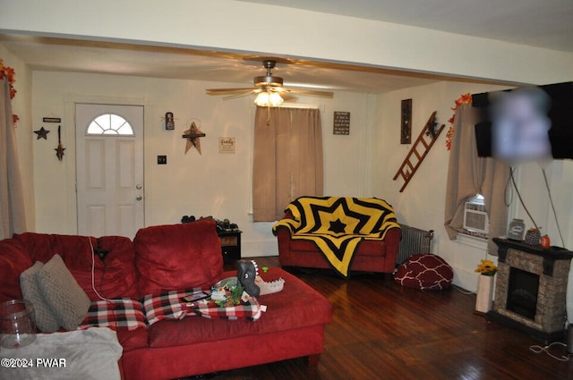 living room featuring dark wood-type flooring, cooling unit, a stone fireplace, ceiling fan, and radiator heating unit