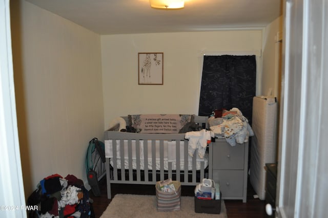 bedroom featuring wood-type flooring and a nursery area