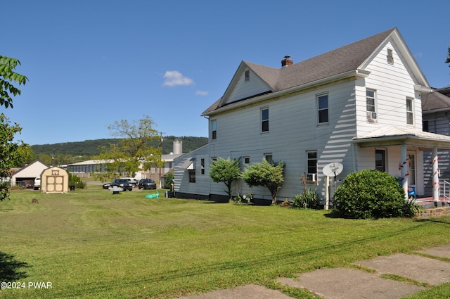 view of side of home featuring a lawn and a storage unit