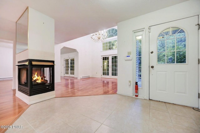 102 Eagle Rock Rd, Lackawaxen, PA 18435 - foyer entrance with a chandelier, a multi sided fireplace, light tile patterned floors, and a baseboard radiator
