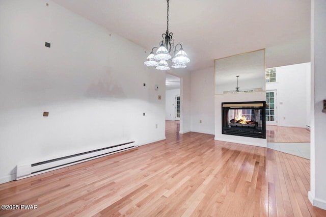 102 Eagle Rock Rd, Lackawaxen, PA 18435 - unfurnished living room featuring a baseboard radiator, hardwood / wood-style flooring, a multi sided fireplace, and a chandelier