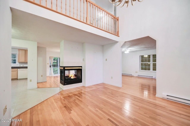 102 Eagle Rock Rd, Lackawaxen, PA 18435 - unfurnished living room featuring a high ceiling, a multi sided fireplace, light wood finished floors, a baseboard radiator, and a chandelier
