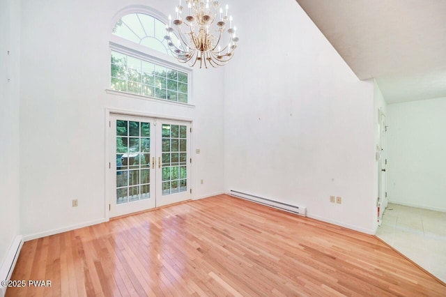 102 Eagle Rock Rd, Lackawaxen, PA 18435 - unfurnished living room with baseboard heating, french doors, hardwood / wood-style flooring, a towering ceiling, and a chandelier