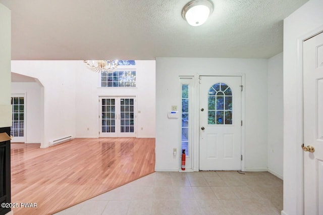 102 Eagle Rock Rd, Lackawaxen, PA 18435 - entrance foyer featuring a baseboard radiator, a chandelier, a textured ceiling, arched walkways, and light tile patterned floors