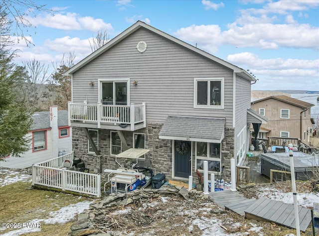 snow covered back of property with a balcony