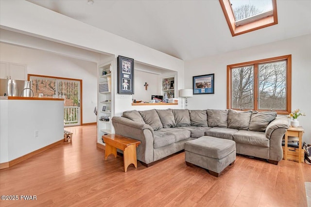 living room with lofted ceiling with skylight and light hardwood / wood-style floors