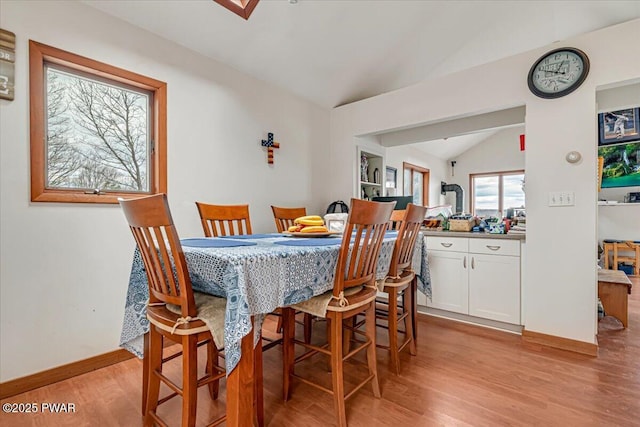 dining room featuring vaulted ceiling and light hardwood / wood-style floors