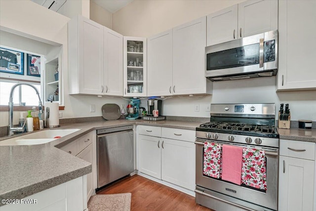 kitchen featuring appliances with stainless steel finishes, light hardwood / wood-style floors, sink, and white cabinets