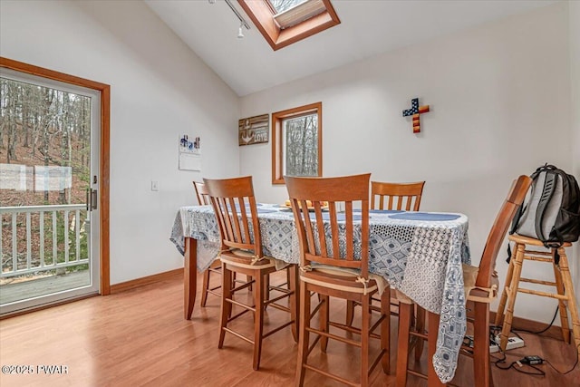 dining room with wood-type flooring and vaulted ceiling with skylight