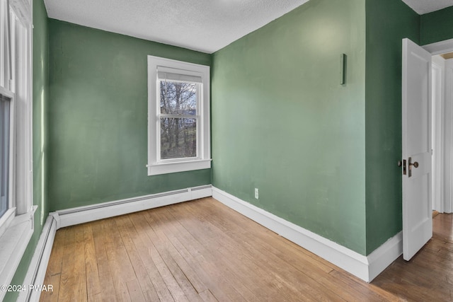 empty room with a baseboard radiator, a textured ceiling, and hardwood / wood-style flooring