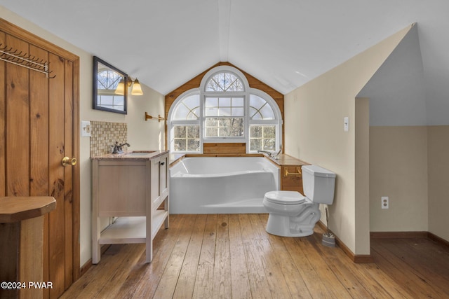 bathroom with a tub, hardwood / wood-style floors, toilet, decorative backsplash, and vanity