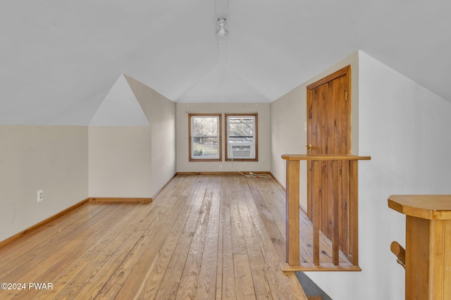 additional living space featuring light hardwood / wood-style floors, lofted ceiling, and cooling unit