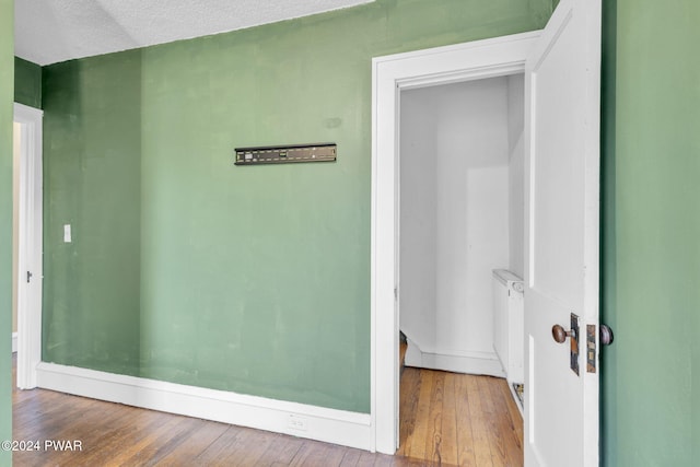 corridor with wood-type flooring and a textured ceiling