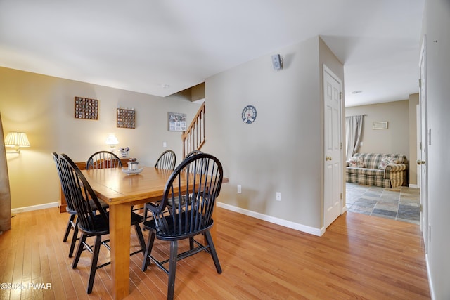 dining space with stairs, light wood finished floors, and baseboards