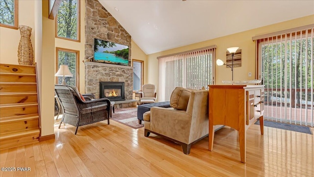 living room with light wood finished floors, high vaulted ceiling, and a fireplace